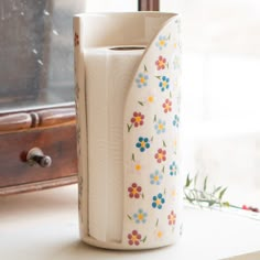 a vase with flowers painted on it sitting next to a dresser and window sill