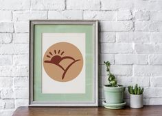 an image of a plant on a shelf next to a framed print with the sun in it