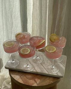 four glasses filled with pink lemonade sit on a tray