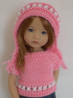 a doll wearing a pink sweater and hat