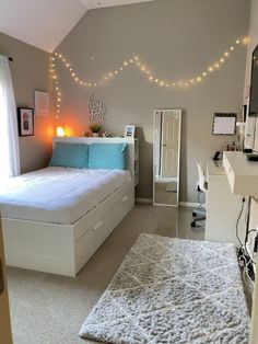 a bed room with a neatly made bed and lights on the wall above it's headboard