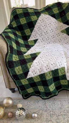 a green and white crocheted blanket sitting on top of a couch next to ornaments