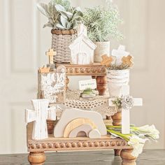 a wooden table topped with potted plants next to a cross and other items on top of it