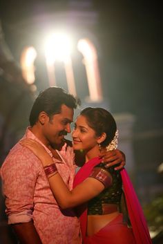 a man and woman embracing each other in front of a building with lights on it