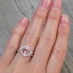 a woman's hand with a pink diamond ring on it