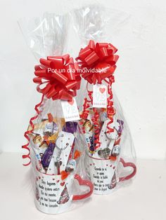 two mugs filled with candy wrapped in red ribbon