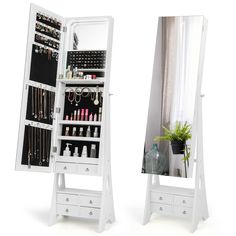 a white jewelry cabinet sitting next to a mirror with drawers and shelves filled with items