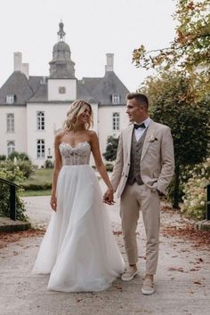 a bride and groom holding hands in front of a large house