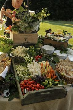 a woman standing in front of a table filled with lots of different types of food