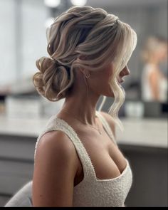 a woman with blonde hair in a low bun hairstyle looking off to the side