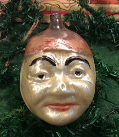 a ceramic face ornament hanging from a christmas tree