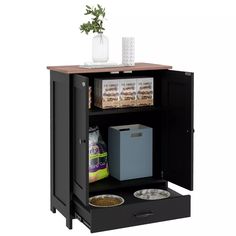 an open cabinet with two bowls and food in it on the shelf next to a potted plant