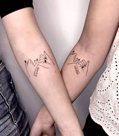 two people holding hands with tattoos on their arms