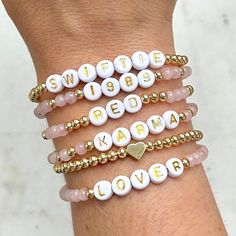 three different bracelets with words and hearts on each one hand, all in gold