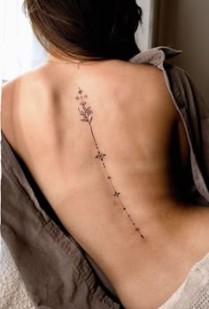 the back of a woman's neck with a small flower tattoo on her left side