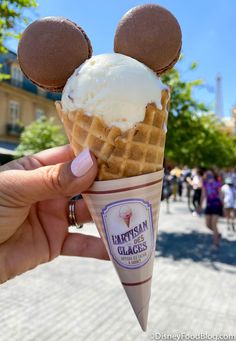 a person holding an ice cream cone with mickey mouse ears on it