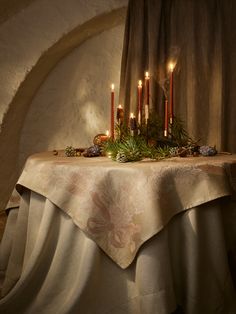 a table topped with candles next to a curtain