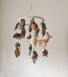 an animal mobile hanging from the ceiling with leaves and acorns attached to it