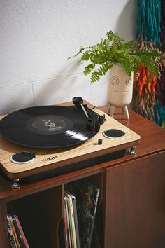 an old record player is sitting on top of a wooden cabinet next to a potted plant