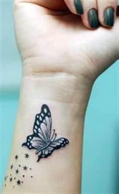 a small butterfly tattoo on the wrist is shown in black and white ink with stars around it