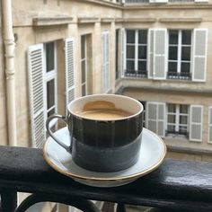 a cup of coffee sitting on top of a saucer in front of a window