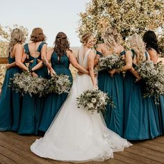 a group of bridesmaids standing on a deck with bouquets in their hands