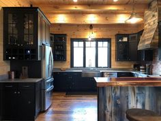 a kitchen with wooden floors and black cabinets, wood counter tops, and an island in the middle