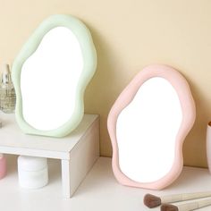 there are two mirrors on the table next to each other, one is shaped like an egg