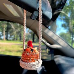 a crocheted bird hanging from a car's front window in the back seat