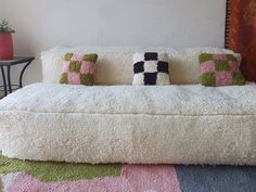 a white couch with four pillows on it and a table in the corner behind it