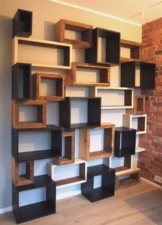 a book shelf made out of wood and some shelves on top of each other in front of a brick wall