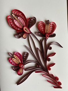 two red flowers are on a white card with gold accents and some brown leaves in the middle