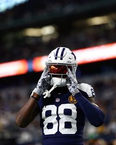 a football player wearing a helmet and holding his hands to his face