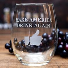 a wine glass with the words make america drink again on it next to some grapes