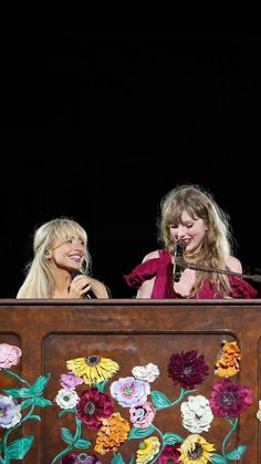 two women are sitting on a stage and one is holding a microphone