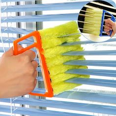 a hand holding a brush and cleaning the blinds