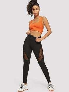 a woman in an orange sports bra top and black mesh leggings poses for the camera