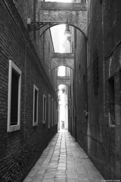 black and white photograph of an alleyway between two buildings with arched windows on each side