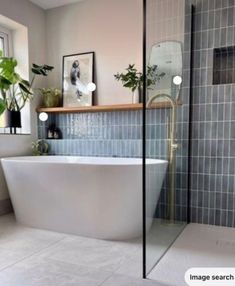 a white bath tub sitting inside of a bathroom next to a sink and window with potted plants