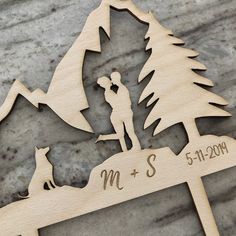 a wooden ornament with a couple and their dog in the mountains