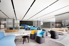 a large room with couches, chairs and tables in front of two sports cars