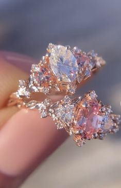 two engagement rings with pink and white diamonds on them are shown in this close up photo