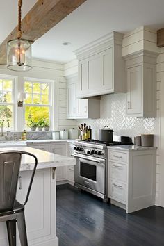 a kitchen with white cabinets and an island in front of a stove top oven next to a window