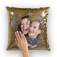 two women hugging each other in front of a gold sequin pillow with an image of them on it