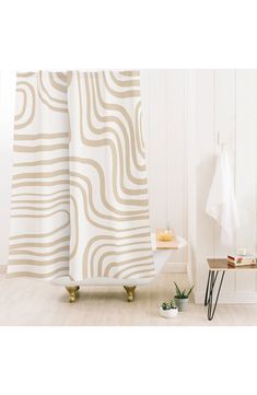 a bath room with a shower curtain and a potted plant on the floor in front of it