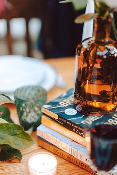 a table topped with books and a vase filled with flowers next to a lit candle