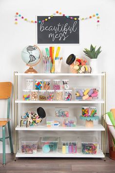 a white book shelf filled with lots of crafting supplies next to a sign that says beautiful mess