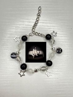 a silver bracelet with black and white beads on it, featuring an image of a woman sitting in a chair