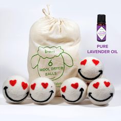 four wool dryer balls with red hearts on them and a bag next to it