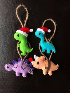 three felt dinosaurs hanging from twine with santa's hat on top and one dinosaur in the middle